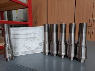 Machined pump components alongside their engineering drawings